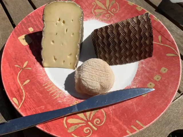 Un plateau de fromages avec une tomme, un fromage de brebis et un petit chèvre, un couteau posé à côté